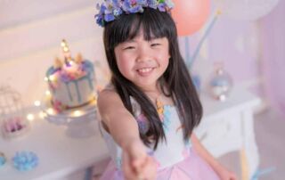 Young girl smiling at her birthday party with cake and decorations in the background