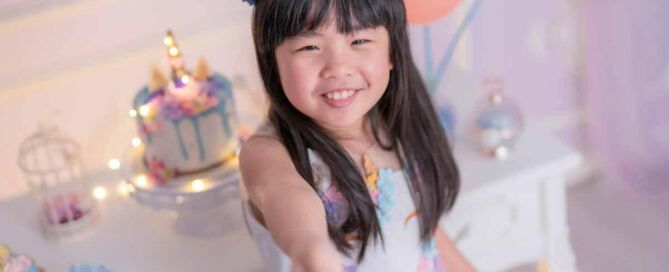 Young girl smiling at her birthday party with cake and decorations in the background