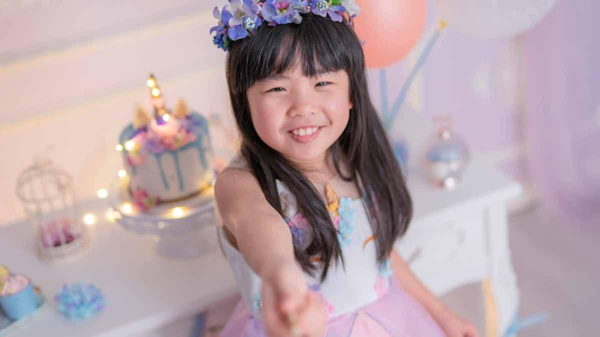 Young girl smiling at her birthday party with cake and decorations in the background