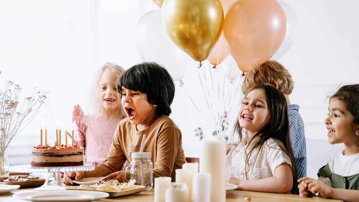Children gathered around a birthday cake during a birthday party celebration