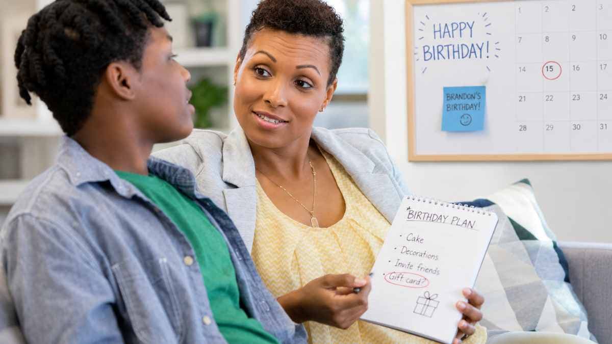 birthday teen plan Mother and teenage son talking about birthday plans while reviewing a family calendar at home.