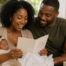 New parents reading a congratulatory card while holding their newborn baby at home
