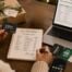 Woman planning a holiday gift card budget while comparing gift card amounts and organizing gifts on a table.
