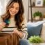 Woman searching through her handbag while holding a gift card in her living room.