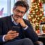 Man browsing his phone at an airport during the holidays, looking for gift ideas while traveling.
